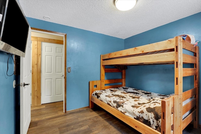 bedroom with a textured ceiling, dark wood-style flooring, and baseboards