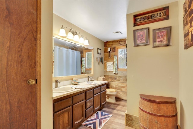 full bath featuring double vanity, visible vents, toilet, and a sink