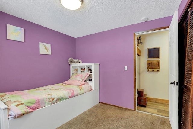 bedroom with baseboards, a textured ceiling, and light colored carpet