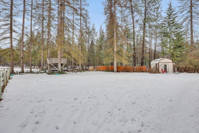 snowy yard featuring a storage unit