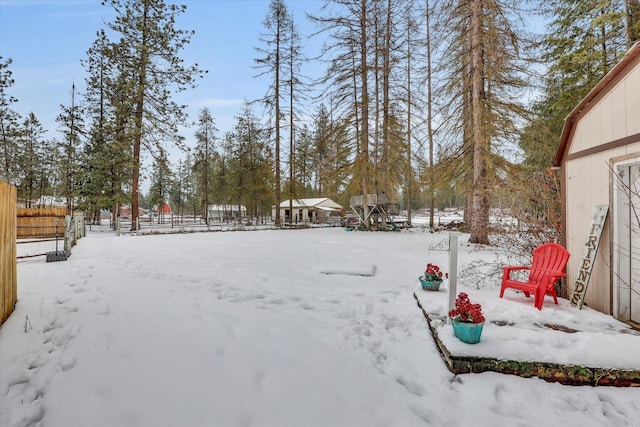 yard covered in snow with a garage and fence