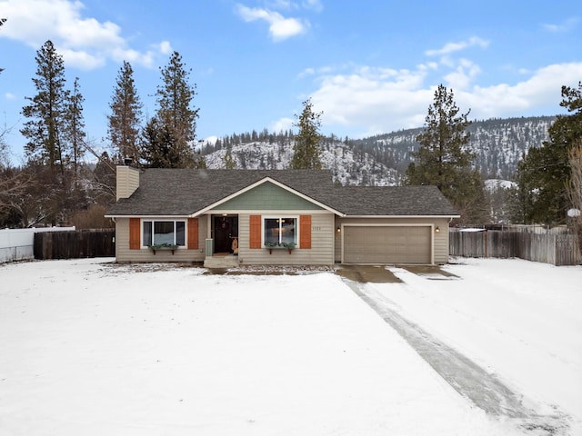 single story home featuring a garage, a mountain view, a chimney, and fence