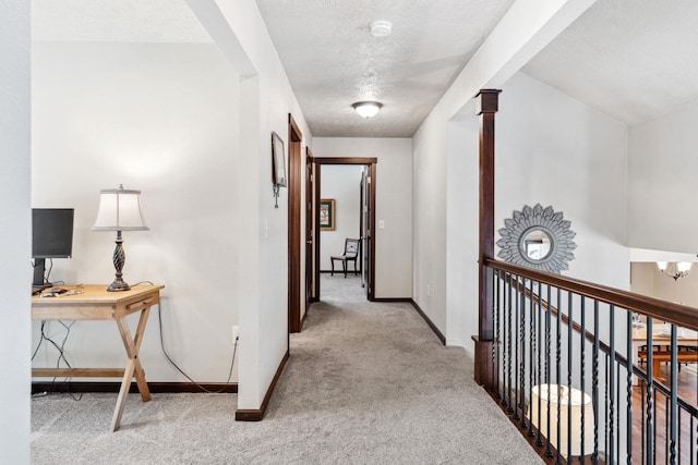 hallway featuring baseboards, carpet flooring, and a textured ceiling