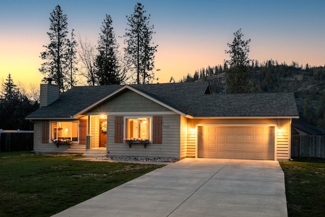view of front of property featuring concrete driveway, a garage, a yard, fence, and a shingled roof