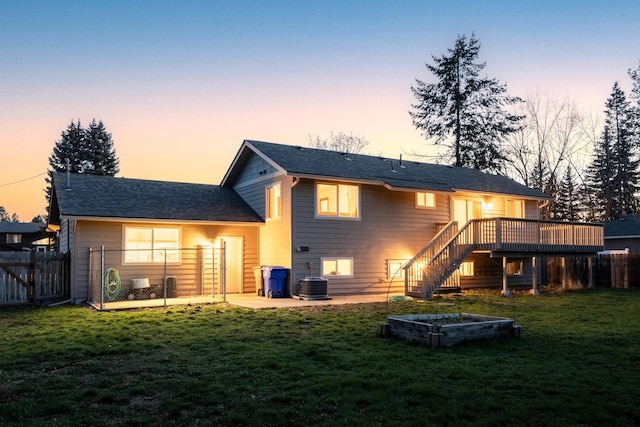 back of property at dusk with central AC, a lawn, fence, stairway, and a wooden deck