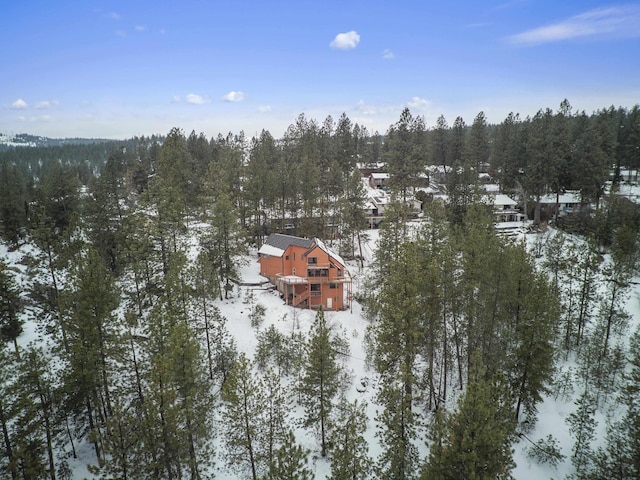 snowy aerial view featuring a wooded view