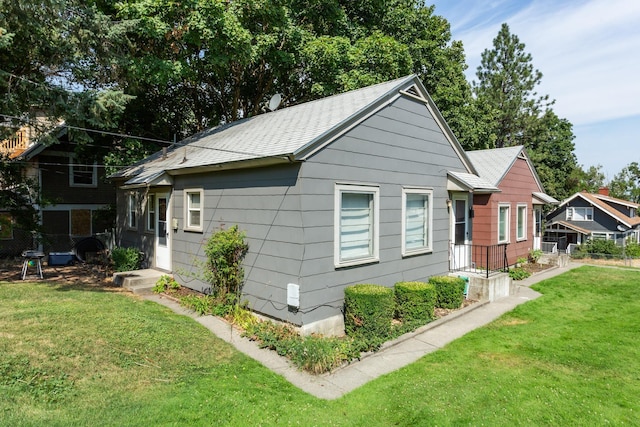 view of property exterior featuring a shingled roof, a yard, and fence