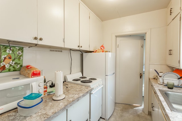 kitchen with a sink, white appliances, white cabinets, and light countertops