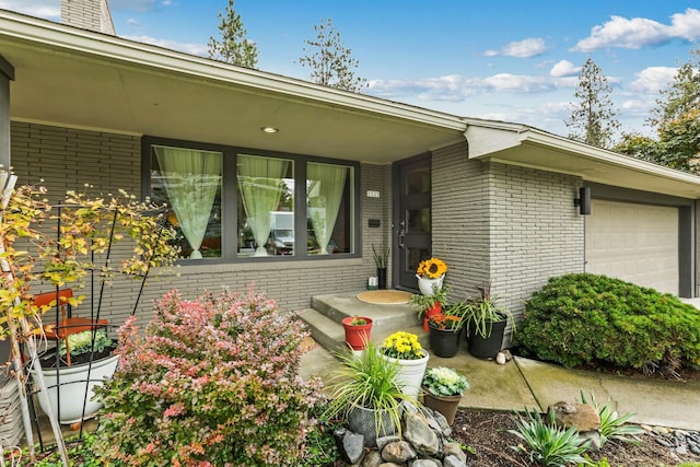 property entrance featuring a garage and brick siding