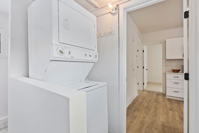 washroom with laundry area, light wood-type flooring, and stacked washer / drying machine