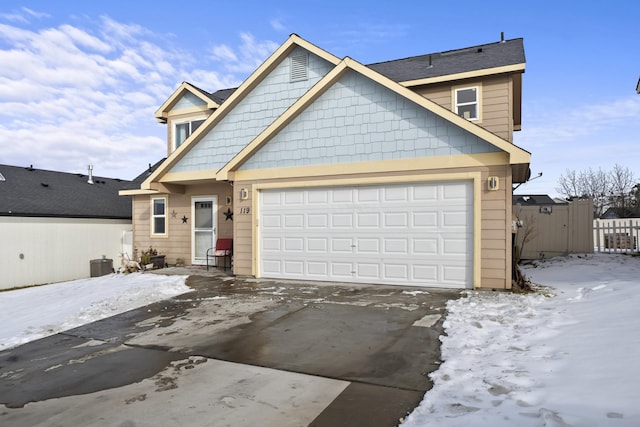 view of front of house with cooling unit, driveway, an attached garage, and fence