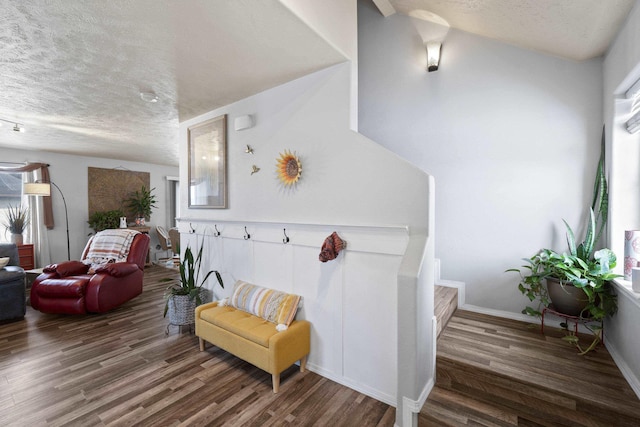 sitting room featuring dark wood-style floors, a textured ceiling, baseboards, and stairs