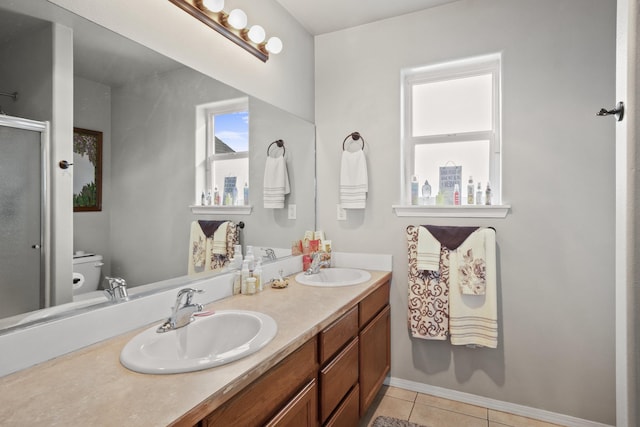 full bath featuring double vanity, a sink, toilet, and tile patterned floors