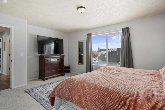 bedroom featuring baseboards, a textured ceiling, and light colored carpet