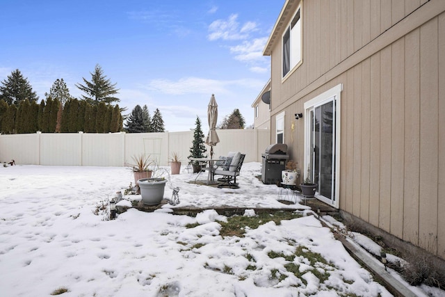 snowy yard featuring a fenced backyard