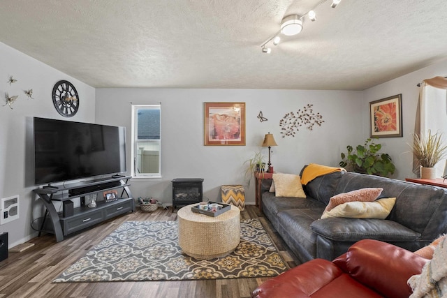 living room featuring a textured ceiling, wood finished floors, and a wood stove