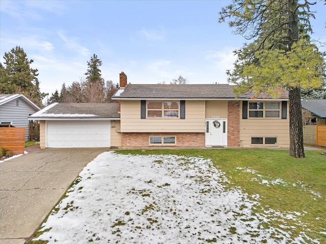 raised ranch with brick siding, a chimney, a front yard, a garage, and driveway