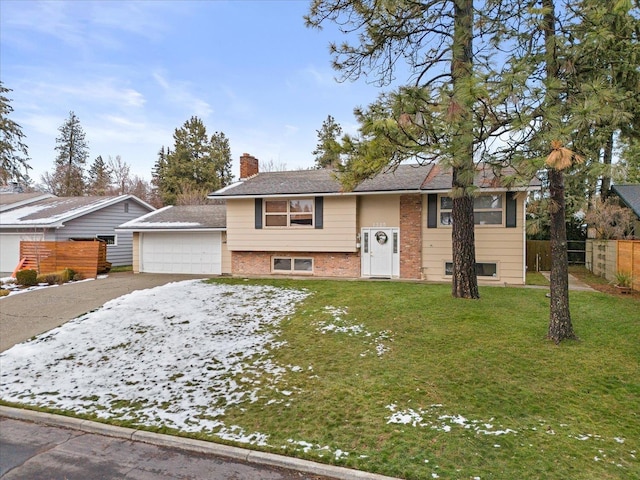 raised ranch featuring driveway, a chimney, fence, a front lawn, and brick siding