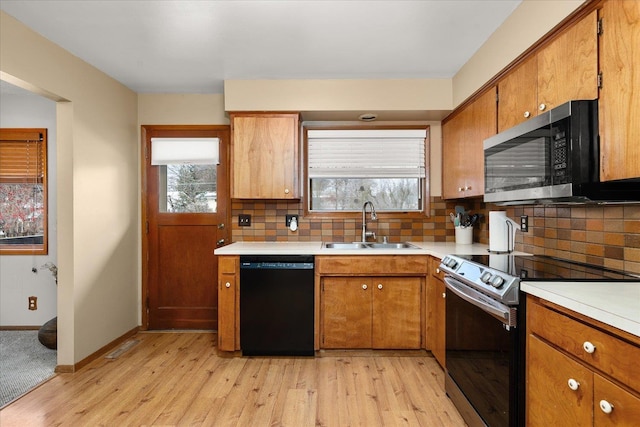 kitchen with brown cabinetry, decorative backsplash, stainless steel appliances, light countertops, and a sink