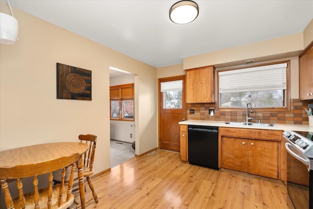 kitchen featuring black dishwasher, brown cabinetry, decorative backsplash, light countertops, and a sink