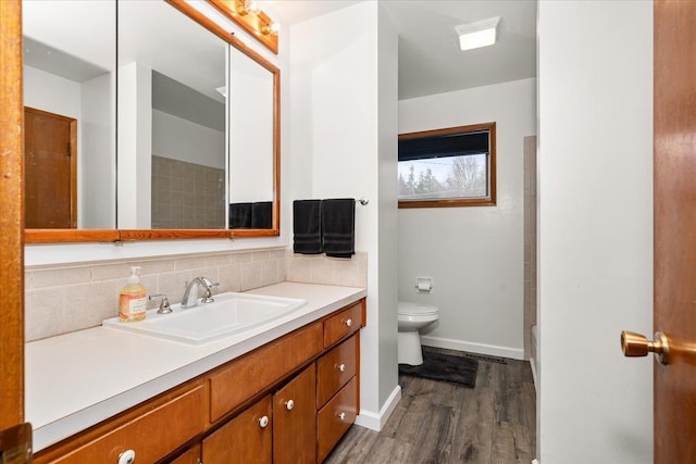 full bathroom featuring toilet, wood finished floors, vanity, baseboards, and decorative backsplash