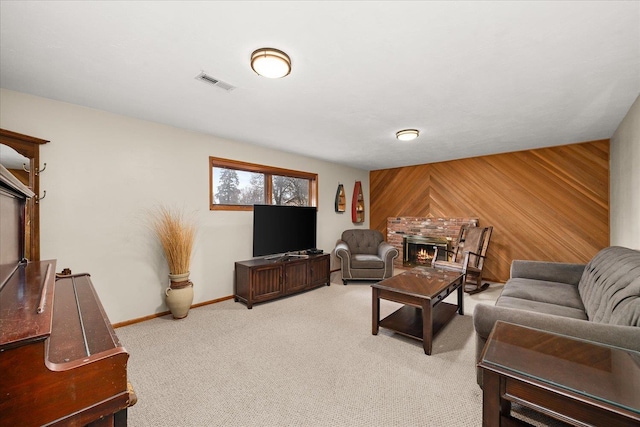 living area with carpet, visible vents, wood walls, a lit fireplace, and baseboards