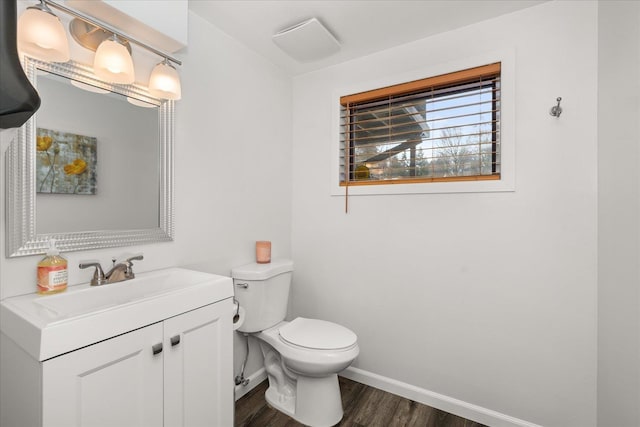 half bath with toilet, vanity, baseboards, and wood finished floors