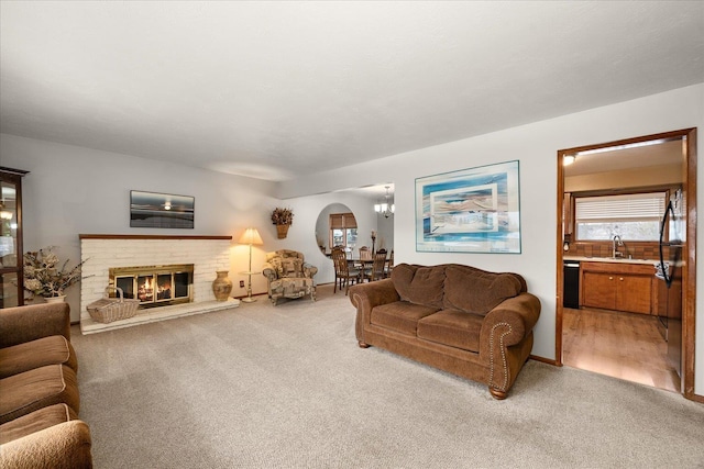 living room featuring arched walkways, a brick fireplace, and light colored carpet