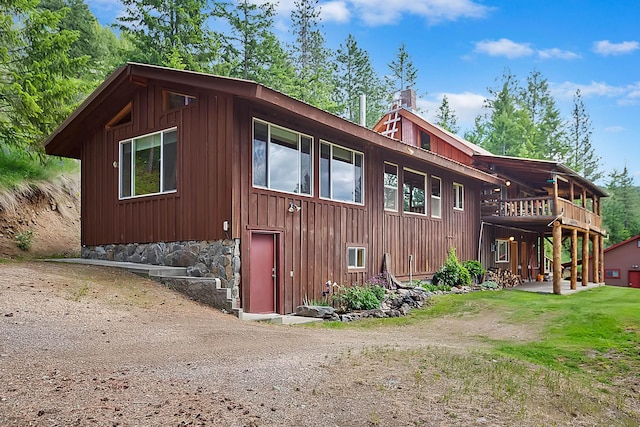 view of home's exterior with a wooden deck, a chimney, and a yard