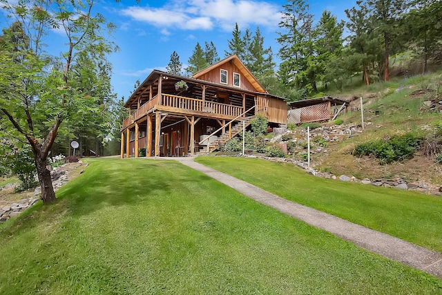 back of property with stairs, a deck, and a lawn