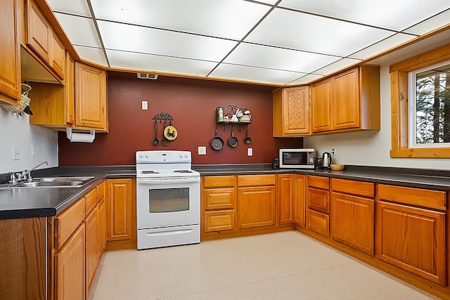 kitchen with dark countertops, white electric stove, brown cabinetry, and a sink