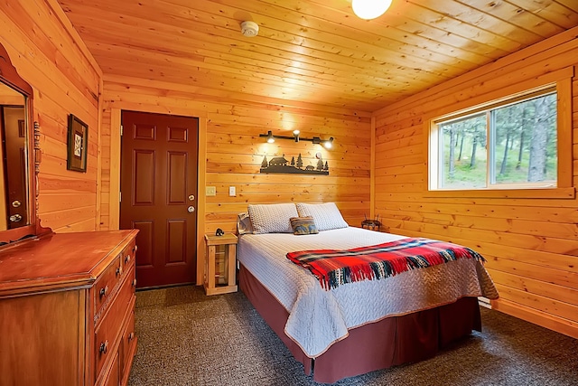 bedroom with dark colored carpet, wooden ceiling, and wood walls