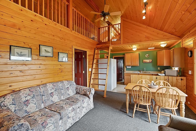 interior space featuring carpet, wood ceiling, ceiling fan, wood walls, and stairs