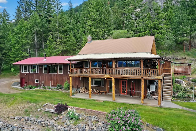 rear view of property featuring a yard, a patio area, metal roof, a wooden deck, and stairs