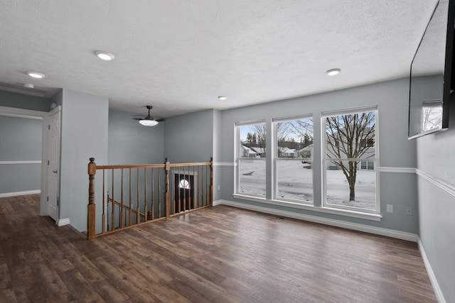 unfurnished room featuring a textured ceiling, recessed lighting, dark wood finished floors, and baseboards