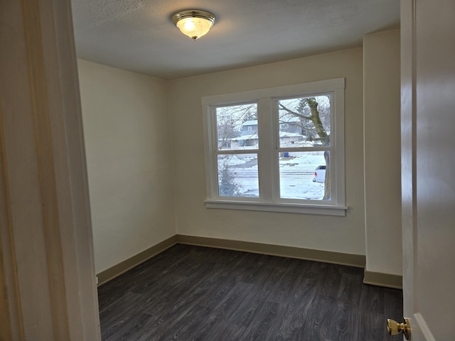 empty room with baseboards and dark wood-type flooring