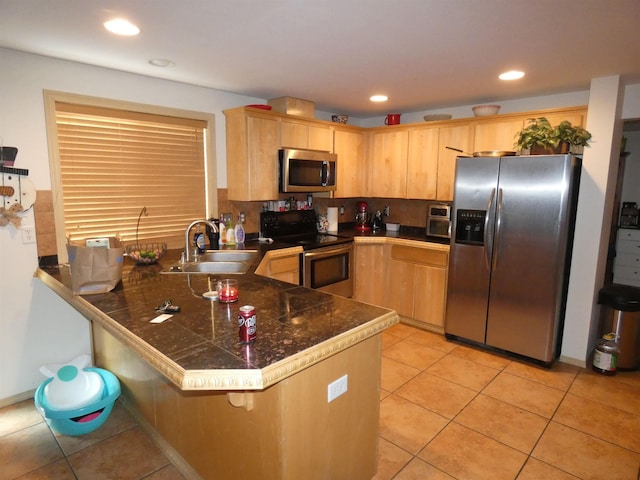 kitchen featuring light brown cabinets, a peninsula, appliances with stainless steel finishes, and a sink