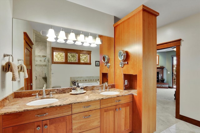 full bath with a fireplace, a sink, a shower stall, and double vanity