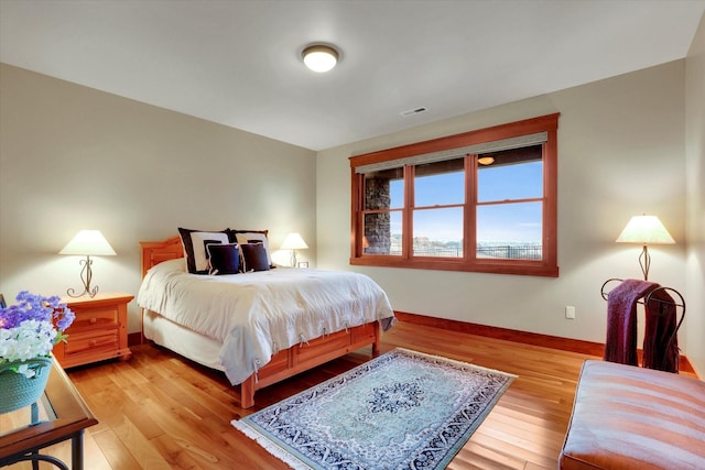 bedroom with light wood-style floors, visible vents, and baseboards