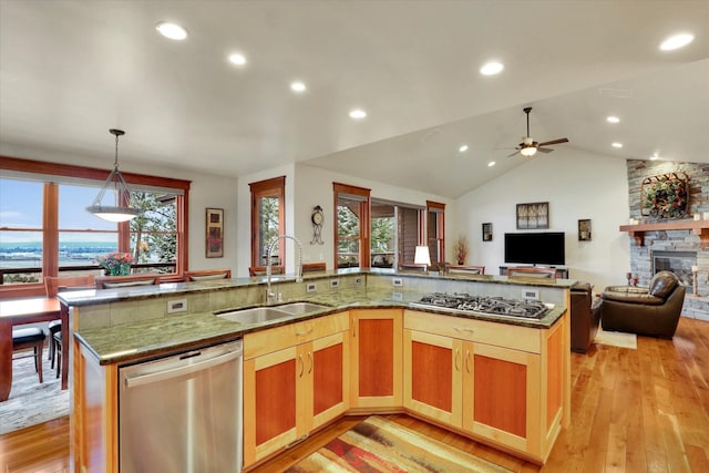 kitchen featuring stainless steel appliances, a spacious island, a sink, open floor plan, and hanging light fixtures