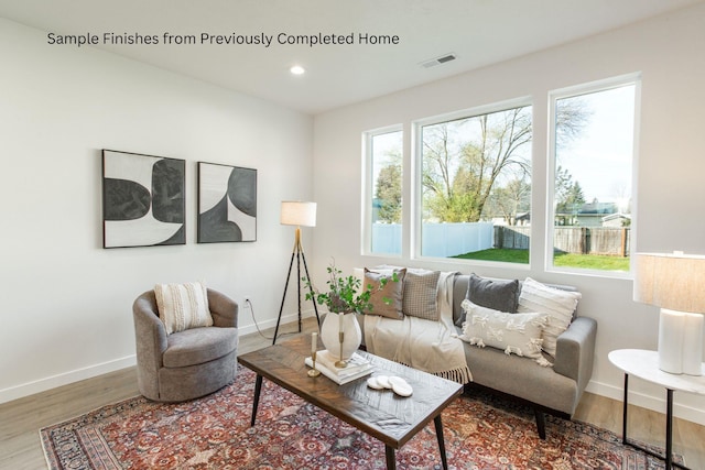 living area featuring a wealth of natural light, visible vents, baseboards, and wood finished floors