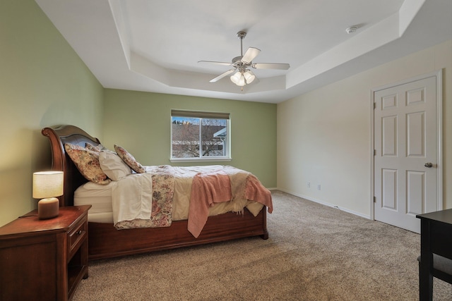 bedroom featuring baseboards, ceiling fan, a raised ceiling, and light colored carpet