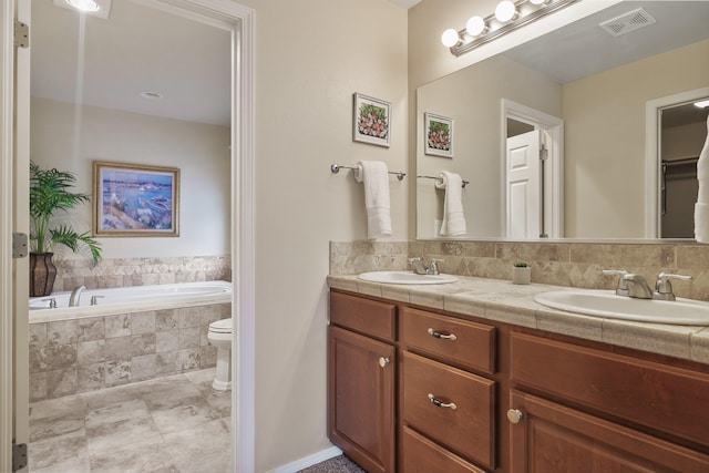 bathroom featuring double vanity, a garden tub, visible vents, and a sink