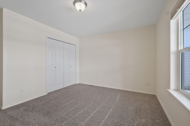 unfurnished bedroom featuring carpet floors, a closet, and baseboards