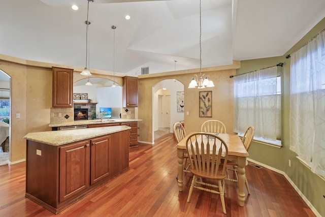 kitchen with arched walkways, decorative light fixtures, dark wood finished floors, and lofted ceiling