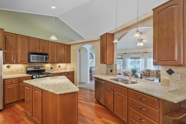 kitchen featuring arched walkways, stainless steel appliances, a peninsula, and a sink