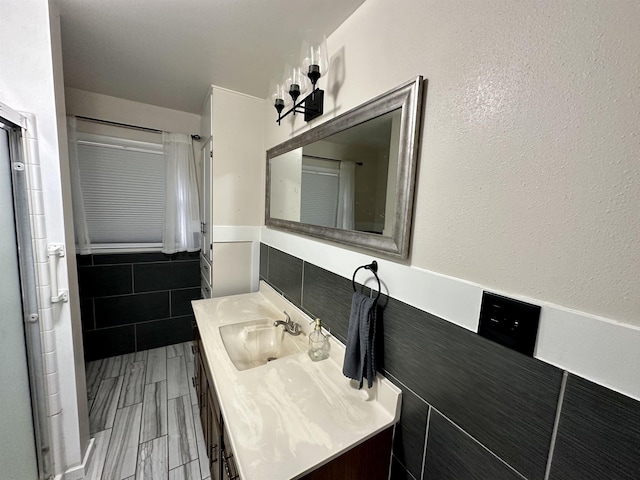 bathroom with wood finish floors, tile walls, and vanity