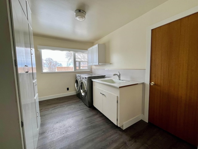 laundry area with dark wood-type flooring, a sink, baseboards, independent washer and dryer, and cabinet space