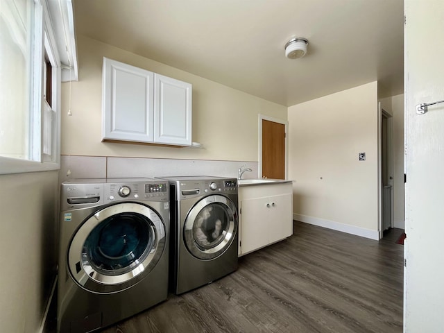 washroom featuring dark wood finished floors, washing machine and clothes dryer, cabinet space, a sink, and baseboards