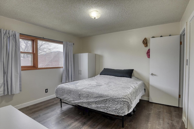 bedroom featuring dark wood-style floors, baseboards, and a textured ceiling